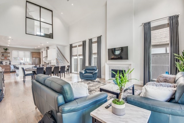 living room featuring a high ceiling, a premium fireplace, plenty of natural light, and light hardwood / wood-style floors