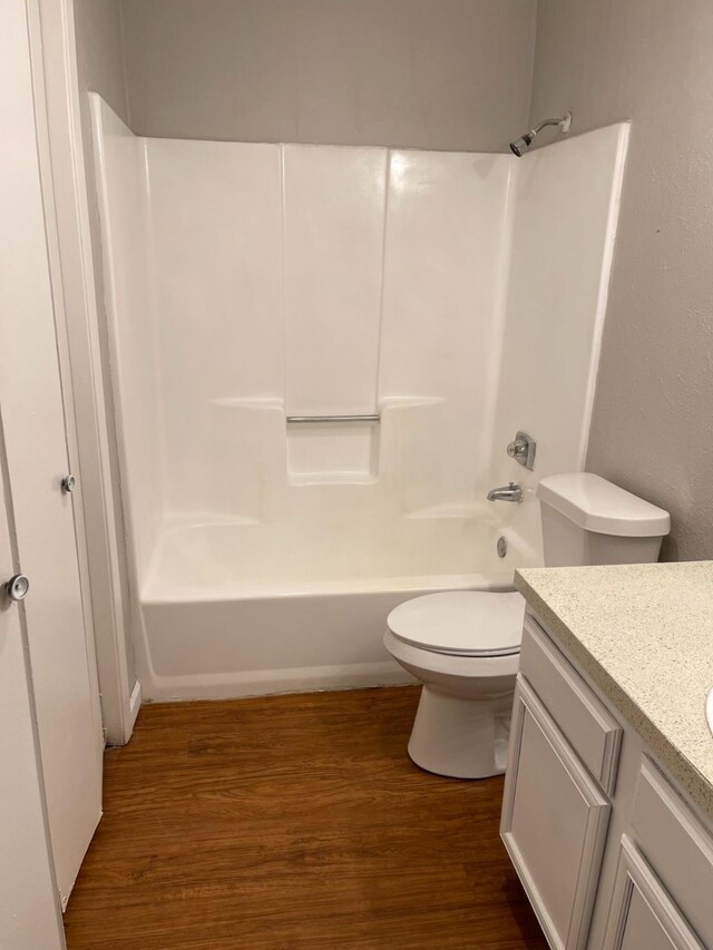 full bathroom featuring wood-type flooring, vanity, washtub / shower combination, and toilet