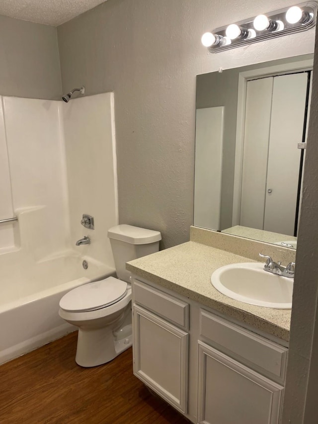 full bathroom featuring wood-type flooring, shower / washtub combination, a textured ceiling, and vanity