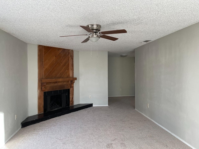 unfurnished living room featuring ceiling fan, a fireplace, carpet, and a textured ceiling