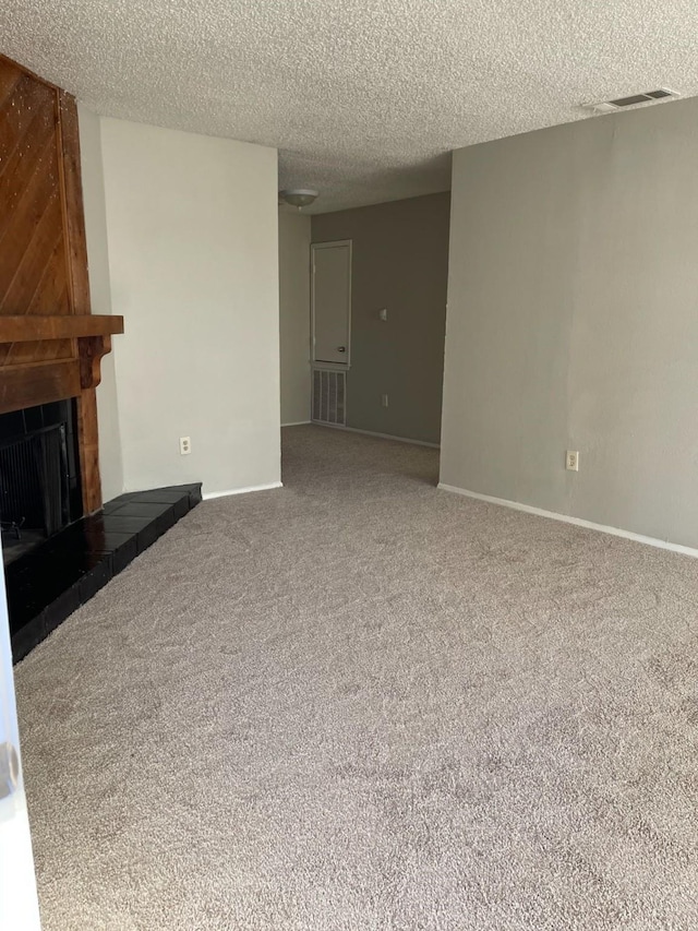 unfurnished living room featuring carpet flooring, a tile fireplace, and a textured ceiling