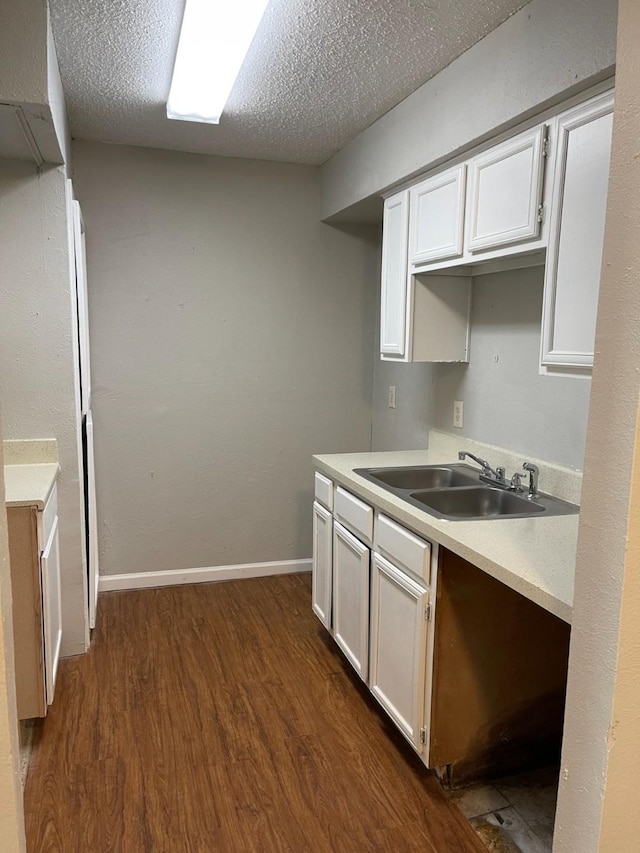 kitchen with dark hardwood / wood-style flooring, sink, a textured ceiling, and white cabinets