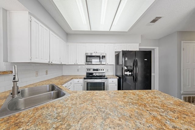 kitchen with stainless steel appliances, sink, white cabinets, and decorative backsplash