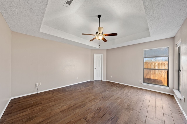 unfurnished room with dark hardwood / wood-style flooring, ceiling fan, a raised ceiling, and a textured ceiling