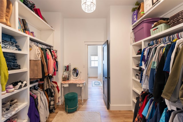 spacious closet featuring a chandelier and light wood-type flooring