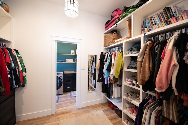 spacious closet with washer / clothes dryer, a notable chandelier, and light hardwood / wood-style floors