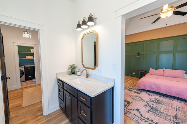 bathroom with hardwood / wood-style flooring, vanity, washer / dryer, and ceiling fan