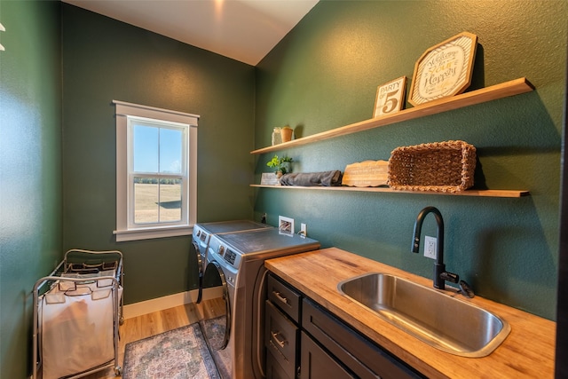 laundry area with cabinets, hardwood / wood-style floors, washer and dryer, and sink