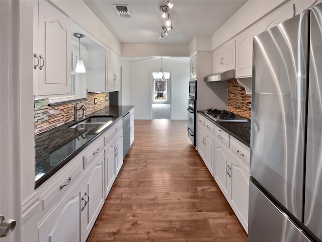 kitchen featuring appliances with stainless steel finishes, sink, hanging light fixtures, and white cabinets