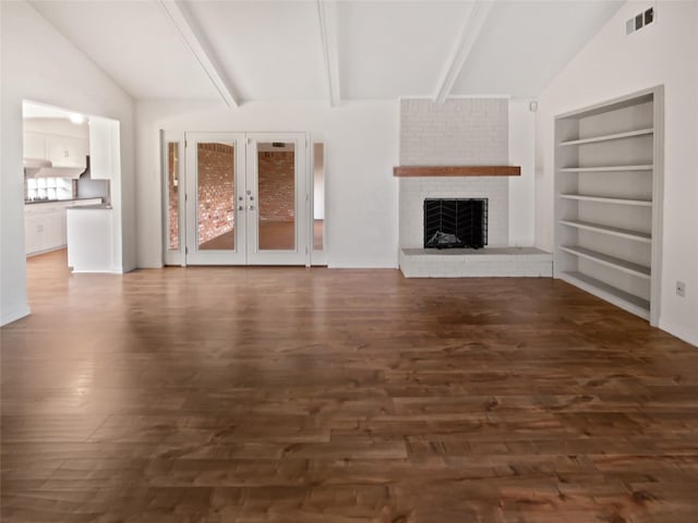 unfurnished living room with built in shelves, dark hardwood / wood-style flooring, lofted ceiling with beams, and a brick fireplace