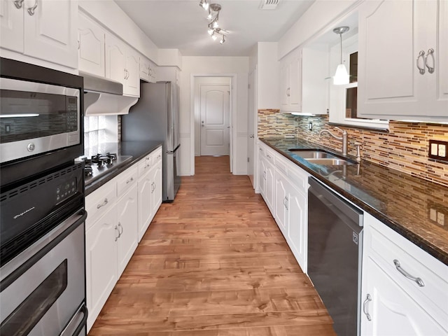 kitchen featuring sink, white cabinetry, hanging light fixtures, appliances with stainless steel finishes, and backsplash