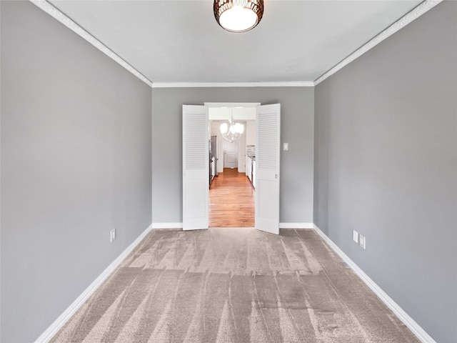 carpeted spare room featuring crown molding and a chandelier