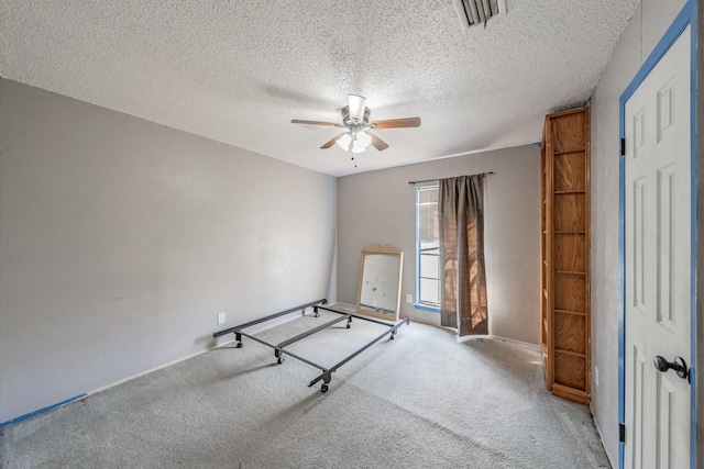 unfurnished bedroom with ceiling fan, light colored carpet, and a textured ceiling