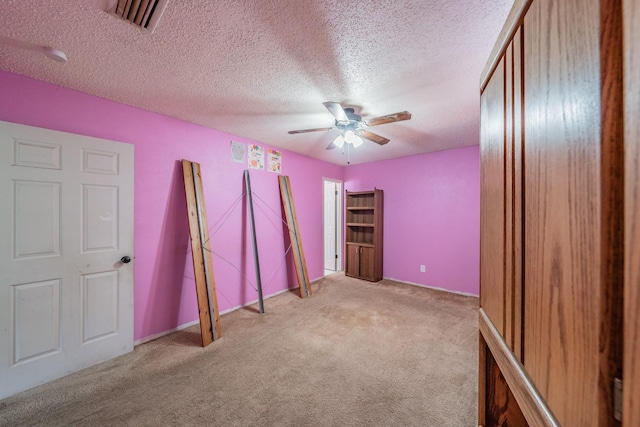 unfurnished bedroom featuring ceiling fan, light colored carpet, and a textured ceiling