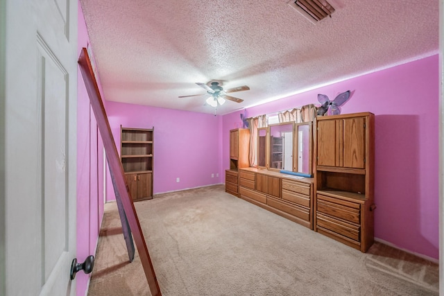 unfurnished bedroom with ceiling fan, light colored carpet, and a textured ceiling