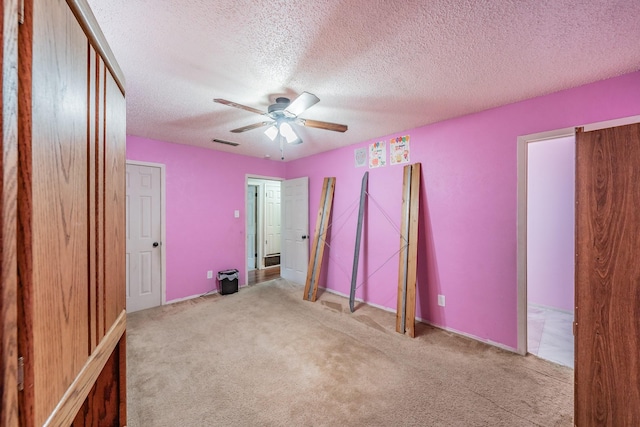 unfurnished bedroom with ceiling fan, light carpet, and a textured ceiling