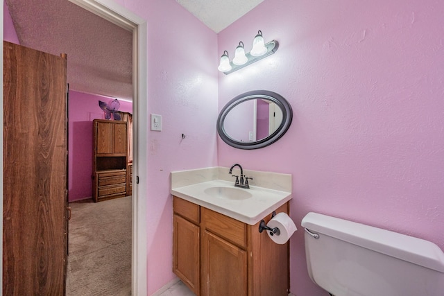 bathroom with vanity, toilet, and a textured ceiling