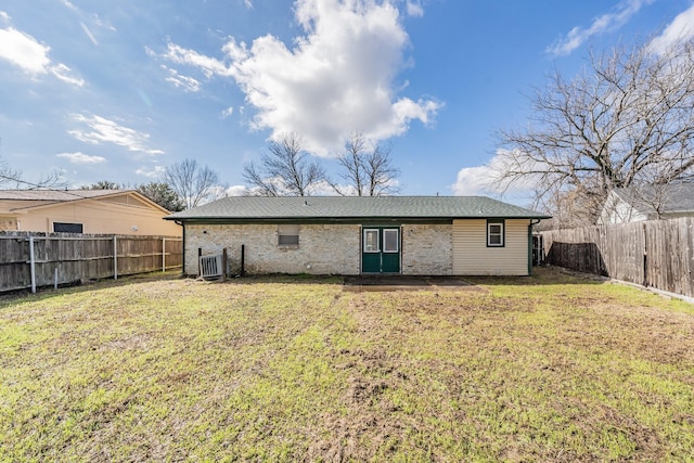 back of property with central AC and a lawn