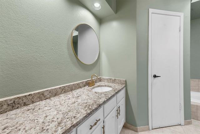 bathroom with vanity, tiled bath, and tile patterned flooring