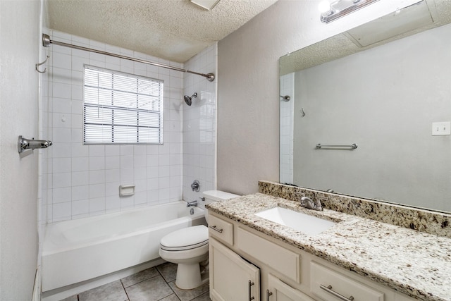 full bathroom with tile patterned flooring, vanity, a textured ceiling, toilet, and tiled shower / bath