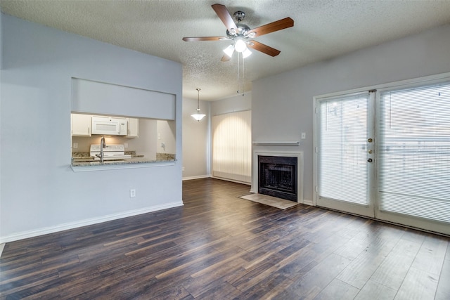 unfurnished living room featuring dark wood-type flooring, ceiling fan, and a textured ceiling