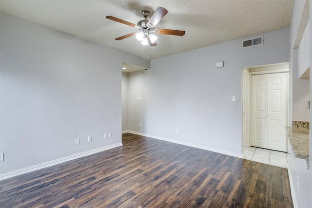 empty room with dark hardwood / wood-style floors, a textured ceiling, and ceiling fan