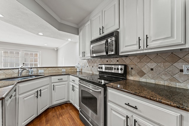 kitchen with white cabinetry, appliances with stainless steel finishes, sink, and dark stone counters