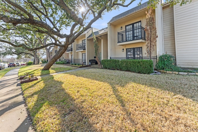 view of front facade with a balcony and a front yard