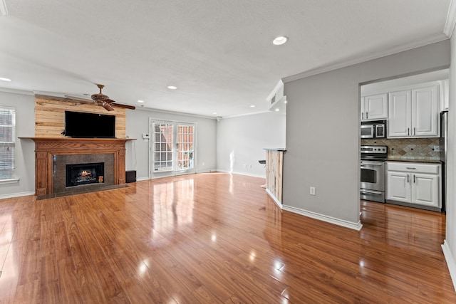 unfurnished living room featuring a large fireplace, plenty of natural light, and ornamental molding