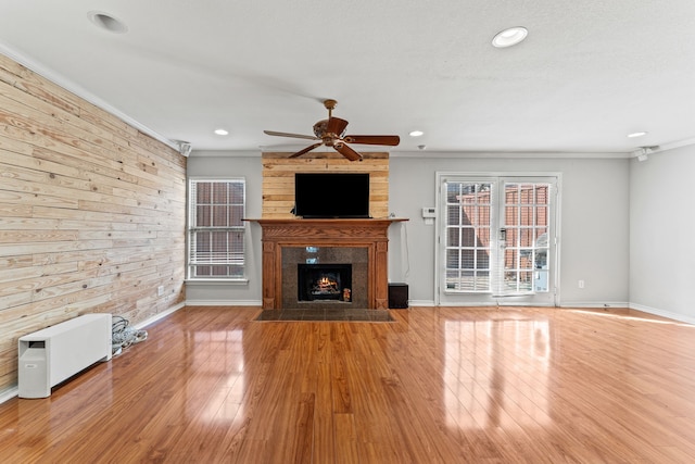 unfurnished living room featuring crown molding, ceiling fan, wood-type flooring, and a fireplace