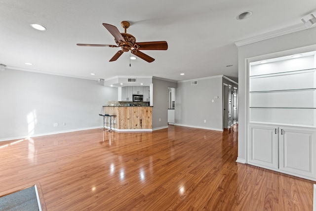 unfurnished living room with hardwood / wood-style flooring, ornamental molding, and ceiling fan