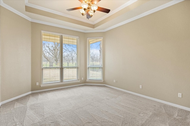 empty room featuring crown molding, ceiling fan, a tray ceiling, and light carpet