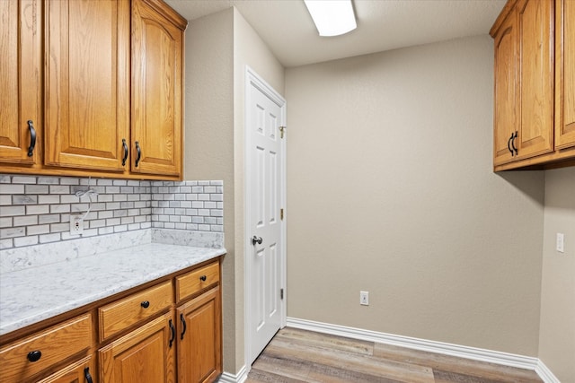 kitchen featuring tasteful backsplash, light hardwood / wood-style flooring, and light stone countertops