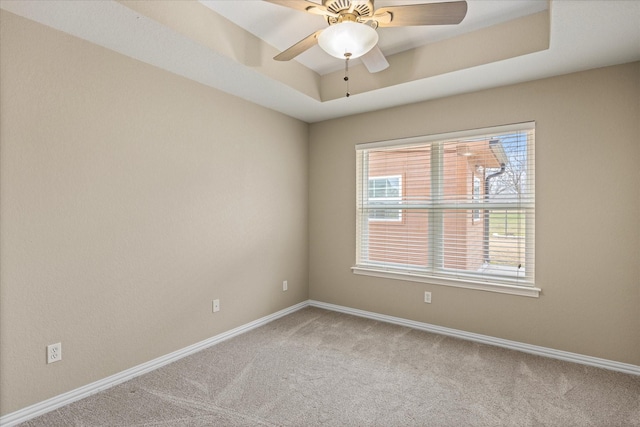 carpeted empty room with ceiling fan and a tray ceiling