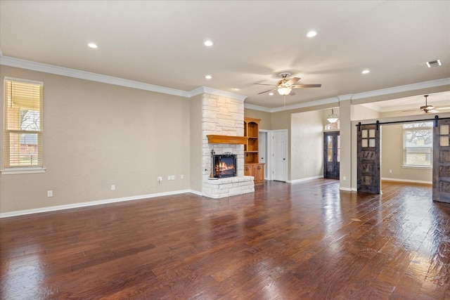 unfurnished living room with dark hardwood / wood-style floors, ceiling fan, a barn door, and crown molding