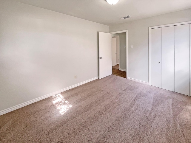 unfurnished bedroom featuring dark carpet and a closet