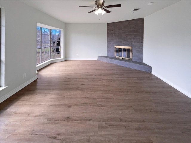 unfurnished living room with a tiled fireplace, ceiling fan, and dark hardwood / wood-style flooring