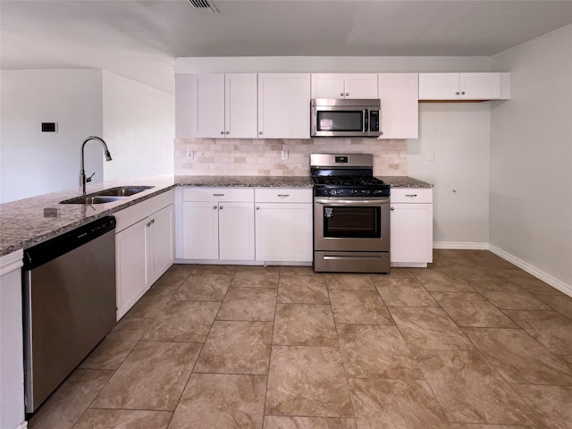 kitchen featuring sink, light stone counters, tasteful backsplash, appliances with stainless steel finishes, and white cabinets