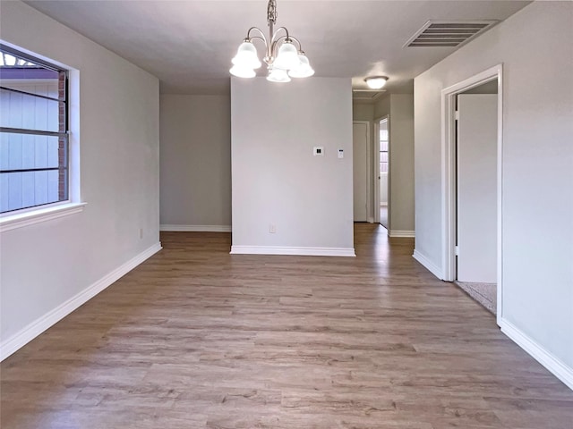 unfurnished dining area featuring an inviting chandelier and light hardwood / wood-style floors