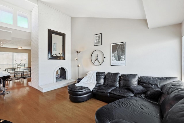 living room featuring wood-type flooring, a fireplace, and high vaulted ceiling