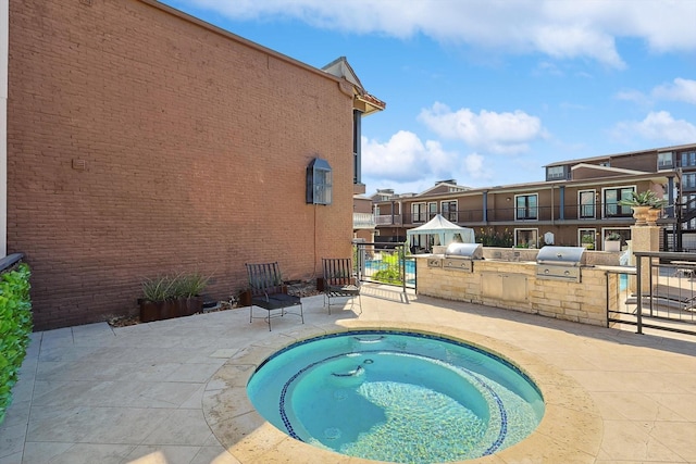 view of swimming pool with an in ground hot tub, an outdoor kitchen, a grill, and a patio area