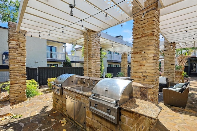 view of patio featuring an outdoor kitchen, a grill, sink, and a pergola