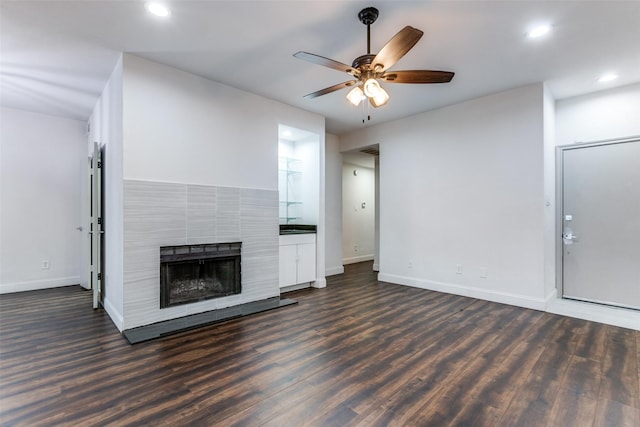 unfurnished living room featuring dark hardwood / wood-style flooring, a tile fireplace, and ceiling fan