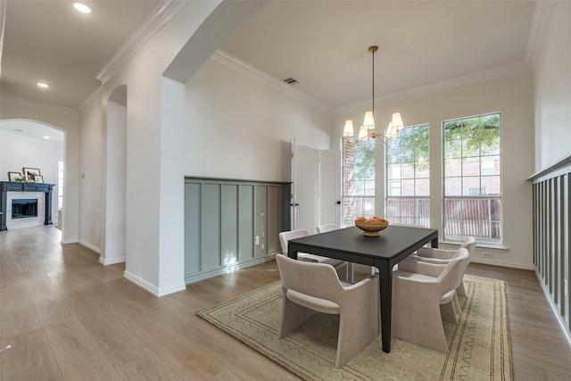 dining room with a notable chandelier, light hardwood / wood-style flooring, and ornamental molding