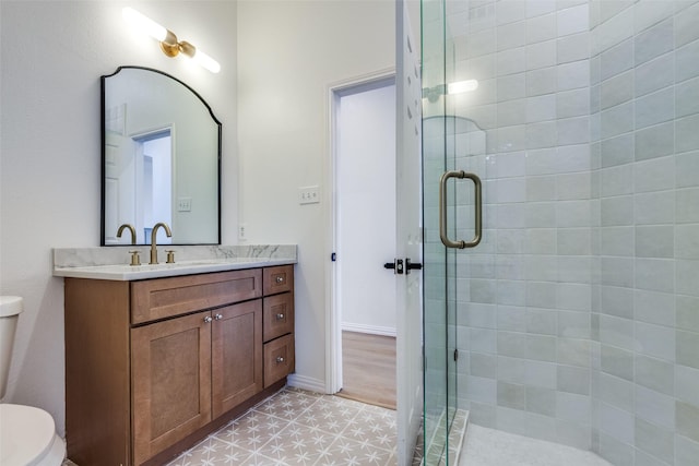 bathroom with vanity, toilet, and a shower with door