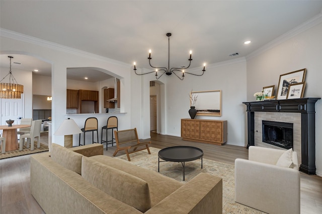 living room featuring crown molding, a chandelier, and light wood-type flooring