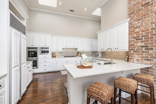 kitchen featuring crown molding, black cooktop, a breakfast bar area, and white cabinets