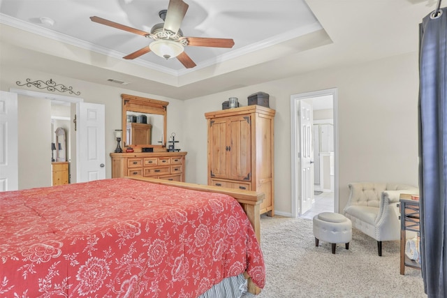 bedroom with crown molding, light colored carpet, ensuite bathroom, and a tray ceiling