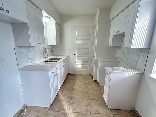 kitchen featuring white cabinetry, light tile patterned floors, sink, and backsplash