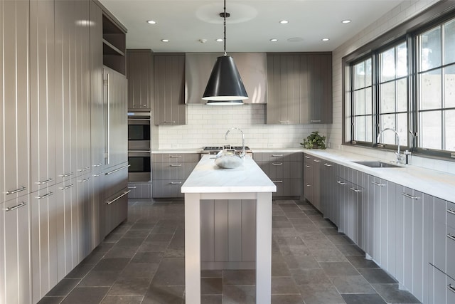 kitchen featuring sink, gray cabinetry, a center island, pendant lighting, and backsplash